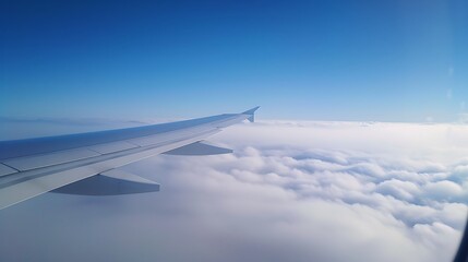 Fototapeta premium Stunning aerial scene captured from an airplane window at cruising altitude with an endless view of clouds below and the airplane wing contrasting the expansive blue sky above