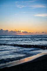 Serene ocean sunset with vibrant colors and silhouetted clouds above the horizon on Ostia beach