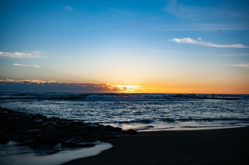 Serene ocean sunset with vibrant colors and silhouetted clouds above the horizon on Ostia beach