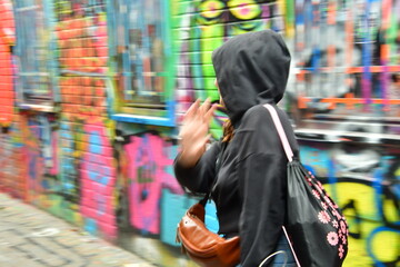 Obraz premium JÓVEN CON CAPUCHA CAMINANDO DE ESPALDAS A LA CÁMARA