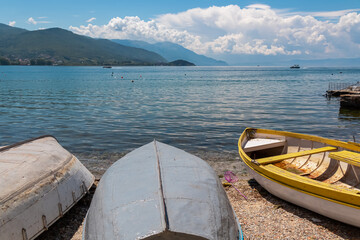 Small fishermen boats are moored on shore of lake Ohrid in North Macedonia. Crystal-clear water...