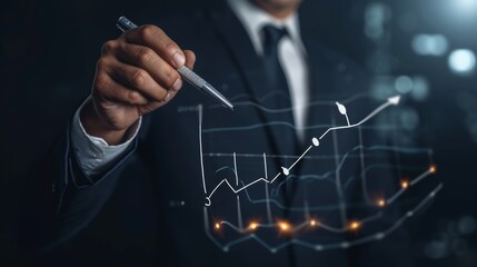 Fototapeta premium A business professional in a suit uses a pen to interact with a digital graph showcasing financial growth trends against a dark office backdrop filled with city lights