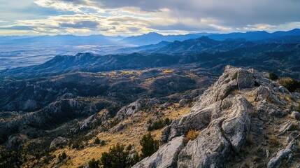 Naklejka premium Mountain range with a cloudy sky in the background. The mountains are covered in trees and rocks