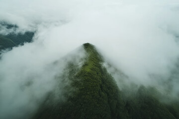 Misty mountain peak emerging through dense clouds at dawn, showcasing the beauty of nature's landscape