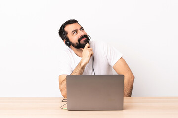 Telemarketer caucasian man working with a headset and with laptop and looking up.