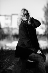 Portrait of a young beautiful blonde girl in a black jacket in nature. Black and white photo.