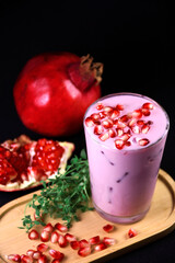 Pomegranate milk drink.  Detox. Proper nutrition. Pink drink in a glass with pomegranate seeds. Pomegranate seeds and greens on a stand.