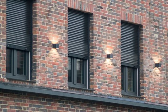 Modern brick wall with illuminated windows and shutters enhancing security and style