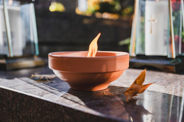 Lit Candle on a Grave Surrounded by Autumn Leaves During All Saints' Day in Poland