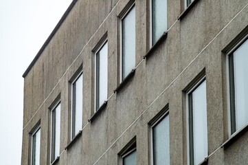 Grey concrete facade of modernist building showing windows and lines