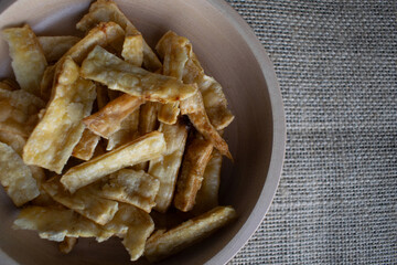 Fried cassava chips in a wooden bowl