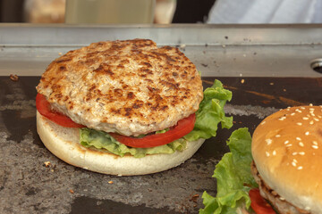 Fried patty with vegetables and bun - burger preparations on a street stall. Close-up