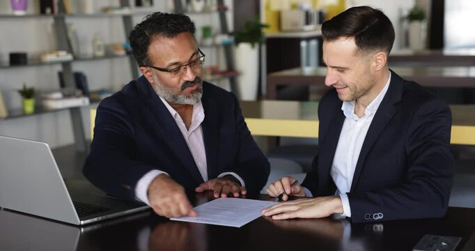 Businessman signing contract after successful negotiations with executive manager or financial advisor at formal meeting in bank. Two businesspeople shaking hands, beginning professional partnership