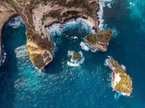 Aerial view of rugged coastal cliffs and turquoise ocean waters.