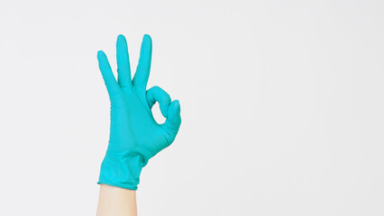Hands is do OK hand sign and wear aqua mint green latex gloves on white background..