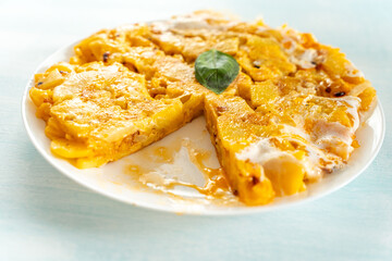 Spanish omelette or Tortilla de patata, with potatoes and onions, on a plate, one piece cut off. Typical Spanish cuisine.