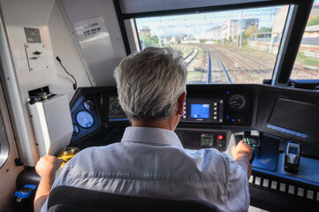 a train driver inside the driver's cabin driving a regional train