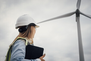 A skilled female engineer is managing wind turbine operations, playing a vital role in construction and engineering to promote environmental sustainability and contribute to a greener planet