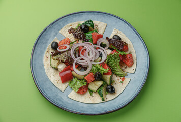 pita bread with fresh salad, olives and olive oil on green background
