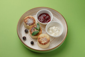 cheesecakes with jam and sour cream on a green background