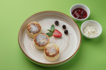 cheesecakes with jam and sour cream on a green background
