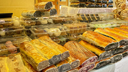 Rows of assorted traditional pastries wrapped in plastic at a market stall, representing holiday treats and food gifting