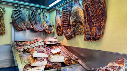An assortment of cured meats hangs in an artisanal deli, highlighting traditional preservation...