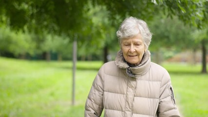 Retired old woman looking at camera relaxed walking in park. Old age senescence concept.MOV