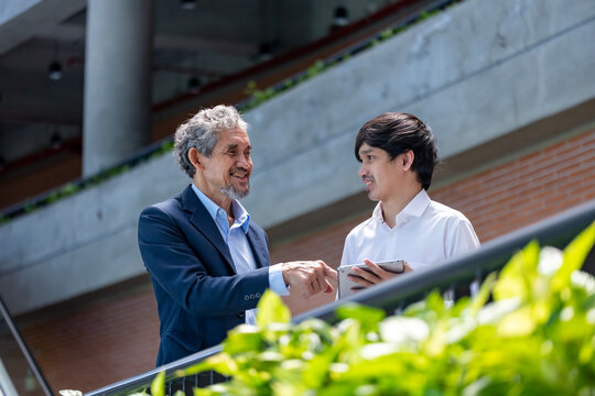 Asian senior professor is giving advice  to the college student on the research thesis while sitting in the university faculty for education, academic and business concept