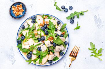 Salad with pear, blueberries, blue cheese, arugula and walnuts. White background, top view