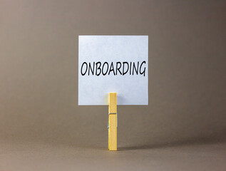 Onboarding success symbol. Concept word Onboarding on beautiful white paper on clothespin. Beautiful grey background. Business onboarding success concept. Copy space.