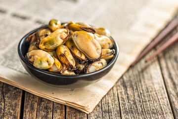 Shelled mussels meat in bowl on wooden table.