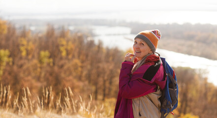 senior woman with a backpack stands on the mountain and looks into the distance and walks in autumn outdoor. copy space. mental health. Slow life.  copy space