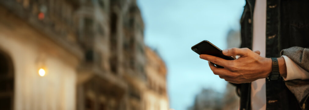 Close-up of male hands with smartphone outdoors