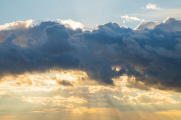 Obraz premium Dramatic clouds illuminated by sunset glow over tranquil sky creates a serene evening atmosphere in nature