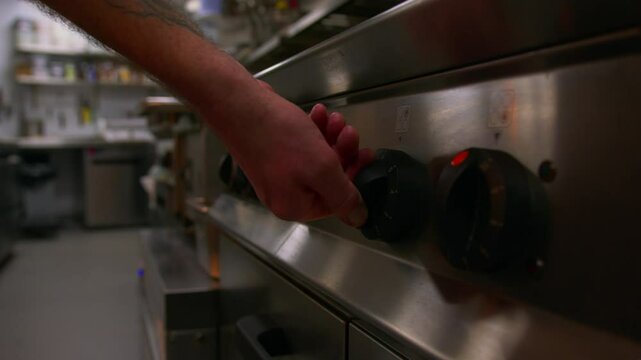 Professional chef turns on the hop and oven in a professional kitchen in slow motion