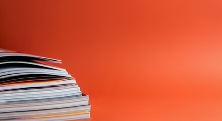 Stack of colorful magazines on vibrant orange background