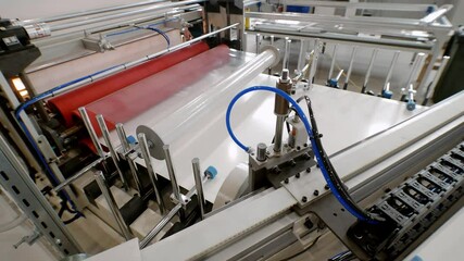 In manufacturing process of sturdy paper, large sheets are wrapped in cellophane for safe transport and then divided into smaller sections using circular saw.