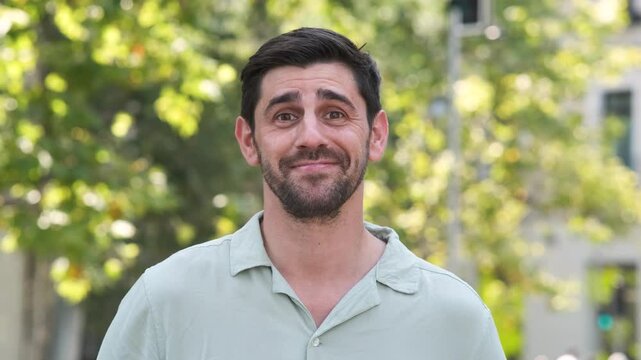Happy man in shrugging shoulders at city park during sunny day