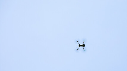 A solitary drone flies high against a clear blue sky, symbolizing technology and modern aerial surveillance challenges