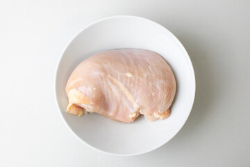 Raw chicken breast in a white bowl on a plain background, perfect for food preparation, healthy eating, or meal planning concepts
