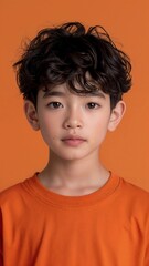 Close up Portrait of a asian boy wearing a brown shirt against an orange background