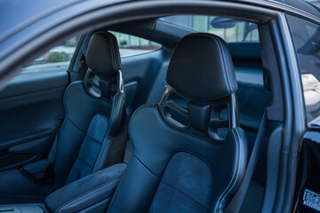 Front seats of a luxury sports car with carbon fiber detailing and premium stitching.