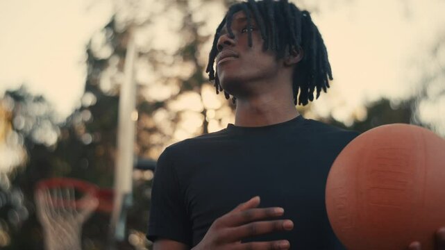 Portrait of a smiling young man playing basketball on a sunny day