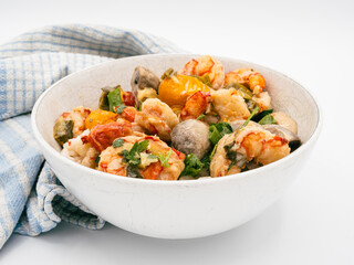 A side view of a delicious Asian shrimp seafood dish in a white bowl, set against a white background with a blue towel, creating a simple yet elegant presentation.
