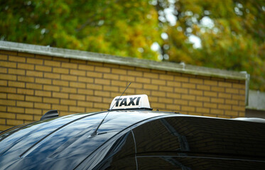 The taxi stands still, its distinctive sign visible, against a backdrop of warm-colored autumn...
