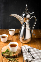 Traditional Arabic Coffee Pot served in Cups with cardamom and mint isolated on wooden table side view of hot drink