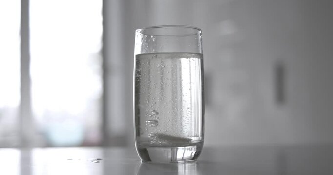 Effervescent aspirin pill in a glass of wate. Soluble tablet shot on super slow motion camera 1000 fps.