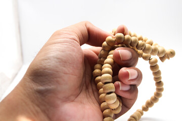 Male hand asian holding muslim beads rosery or tasbih for pray with isolated background.