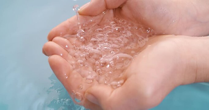 Clean drinking water flows in the palms of the woman hands. Shot on super slow motion camera 1000 fps.